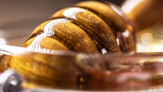 Honey in glass jar with wooden spoon