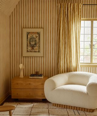 yellow and white striped walls with matching curtains and cream boucle armchair