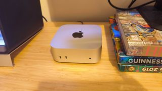 A silver Apple Mac mini (M4) on a wooden desk