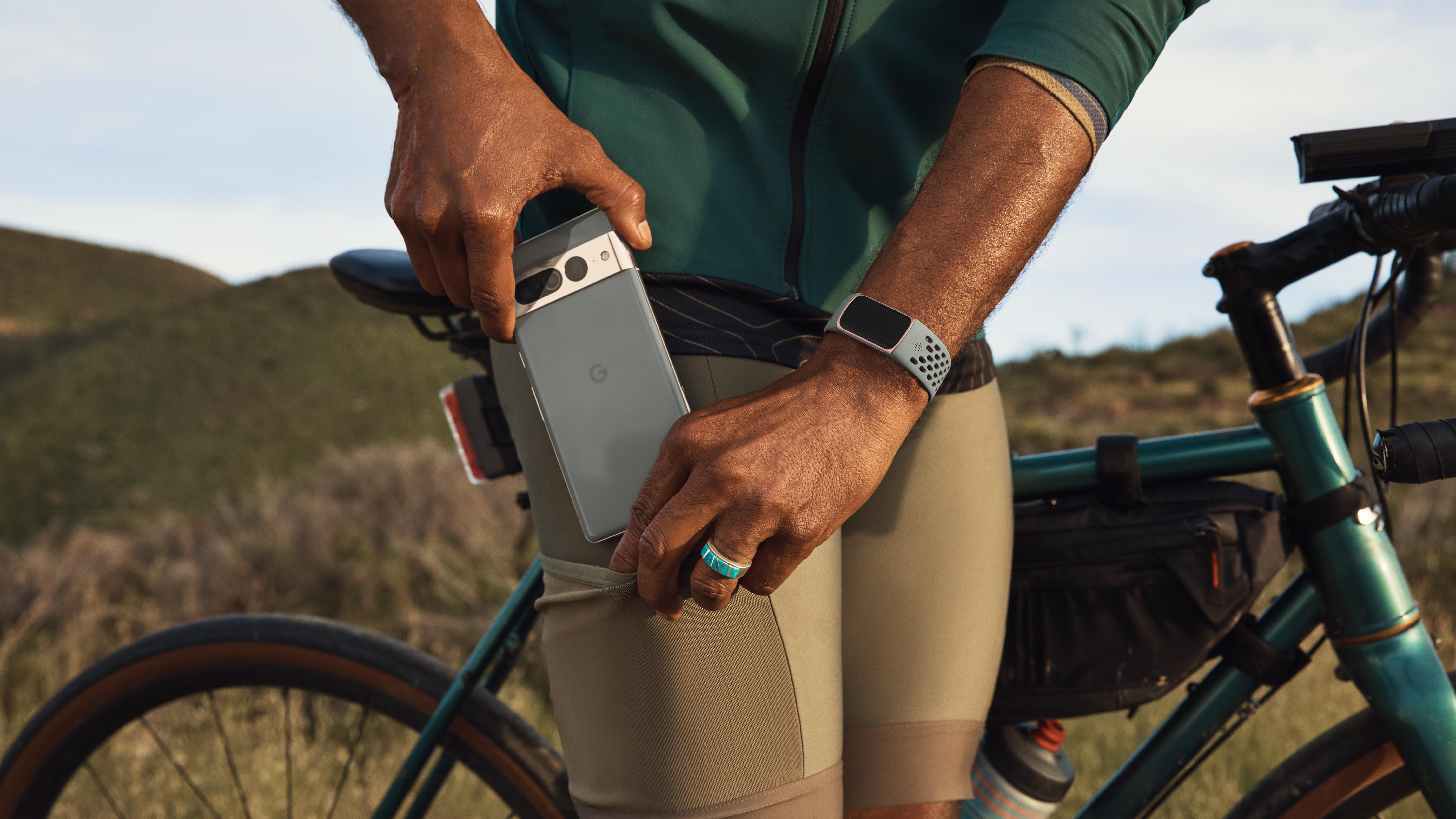 Ein Mann hält sein Google-Telefon und trägt den Fitbit Charge 6