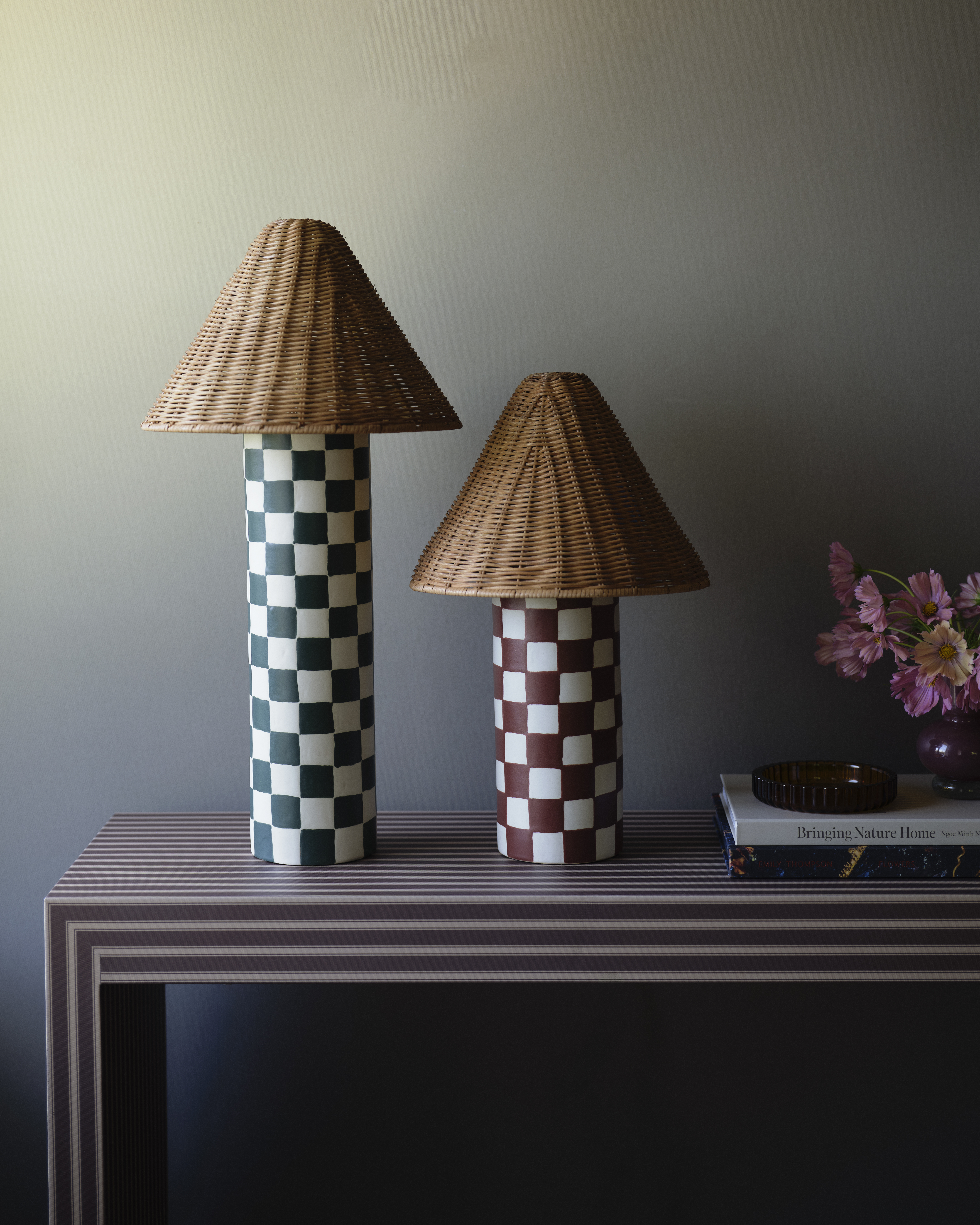 Checkerboard table lamps with rattan shades sitting on a striped entryway bench