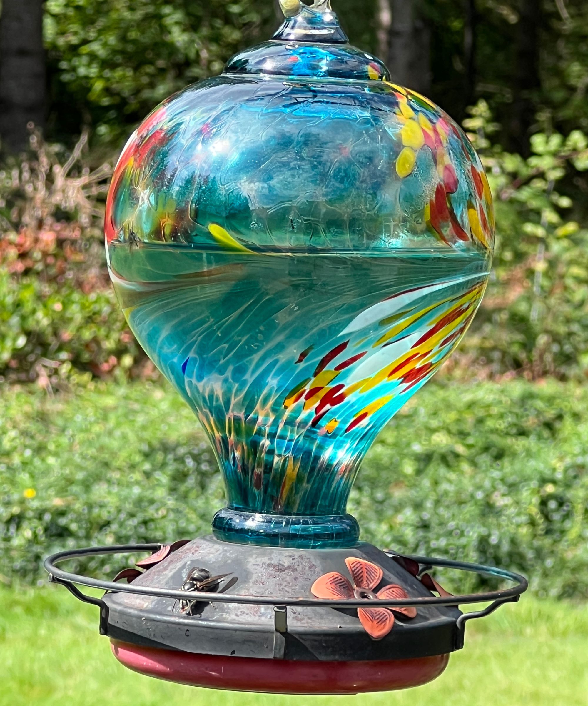 Blue glass hummingbird feeder with red and yellow painted design