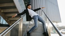 A young man appears to be dancing on a staircase with railings on either side of him.