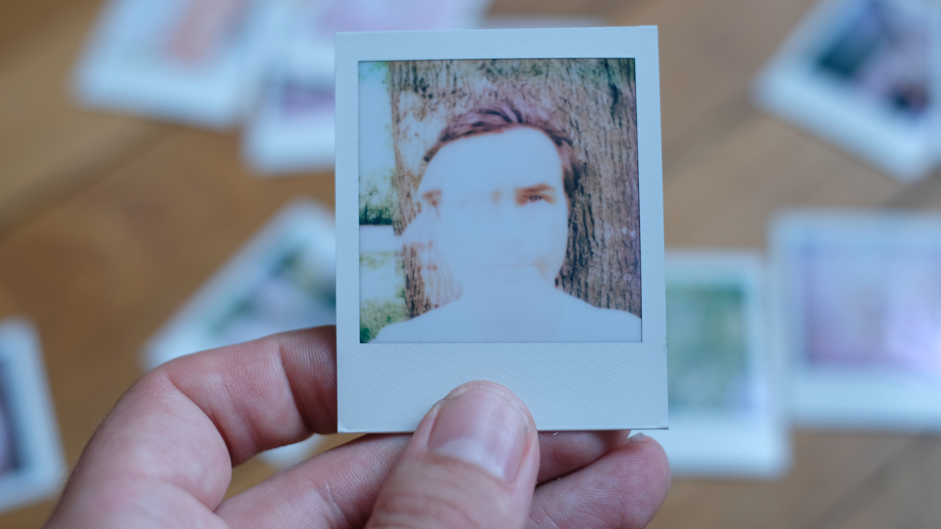 Photograph of prints made with Polaroid Go Gen 3 showing double exposure of man's face in different positions, very bright white in center