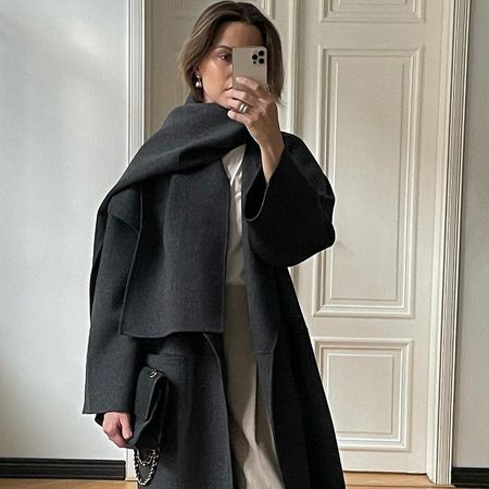 European style influencer Johanna Piispa poses for a mirror selfie wearing a chic 2026 winter outfit idea with a long coat, white tee, and relaxed beige pants