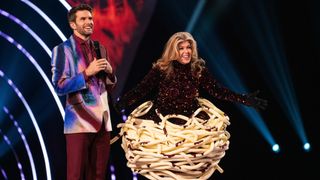 Kate Garraway unmasked as Spag Bol in The Masked Singer 2025 - standing next to Joel Dommett on stage.