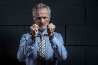 Shadowy image of an older man in handcuffs