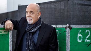 Billy Joel leaning against a fence