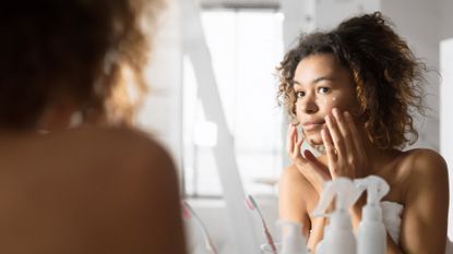 model applying eye cream in her bathroom