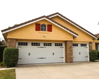 A yellow single-story home with a three-car garage in a carriage door design