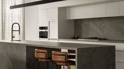 A kitchen with a stone island, with a linear light above the counter 