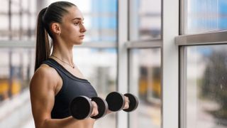 a woman doing a bicep curl with a pair of dumbbells