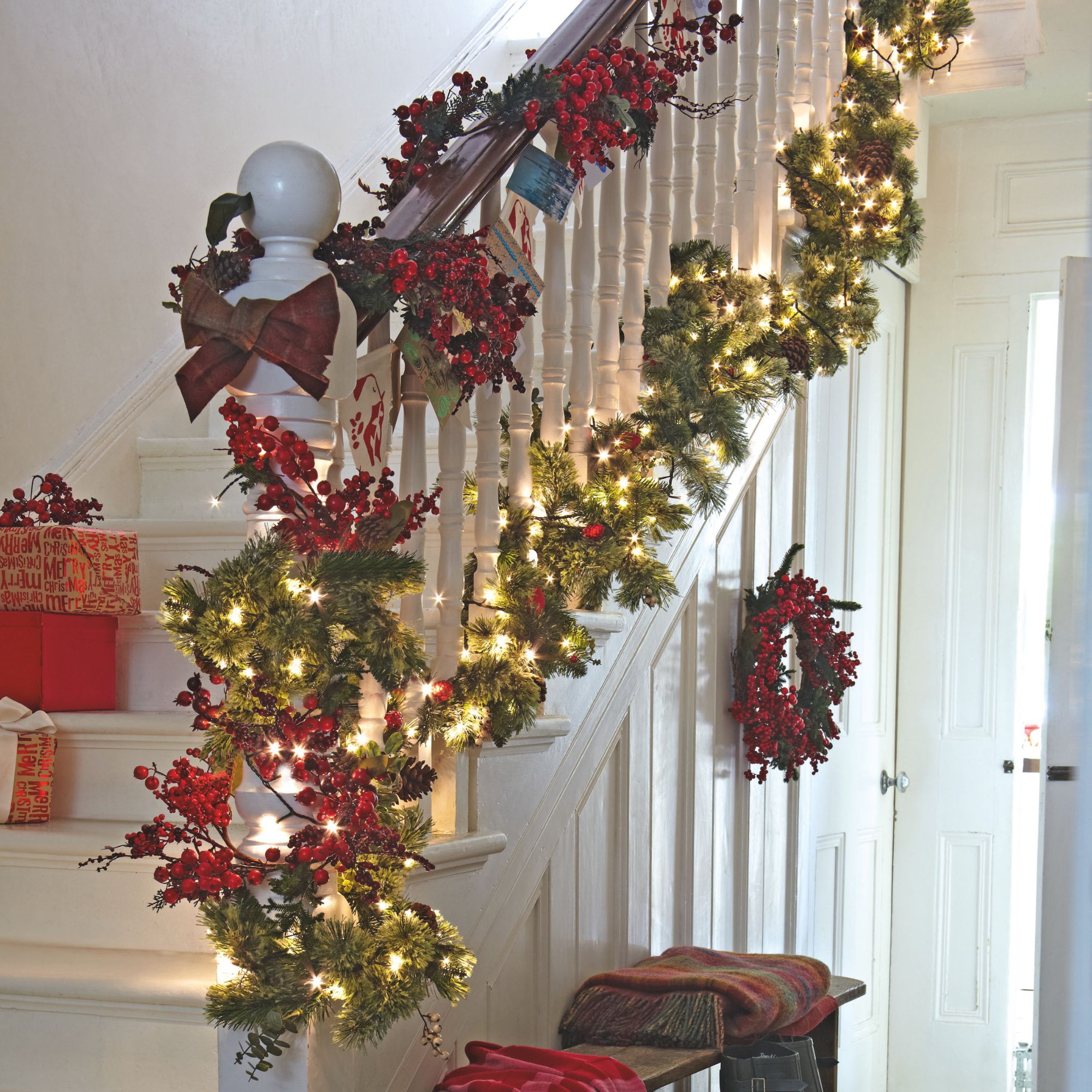 A traditional Christmas garland running up a banister, with red berries and bows