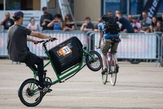 A man pulls a wheelie on a green cargo bike