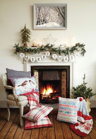 Christmas cushions in a living room with a fireplace and a chair