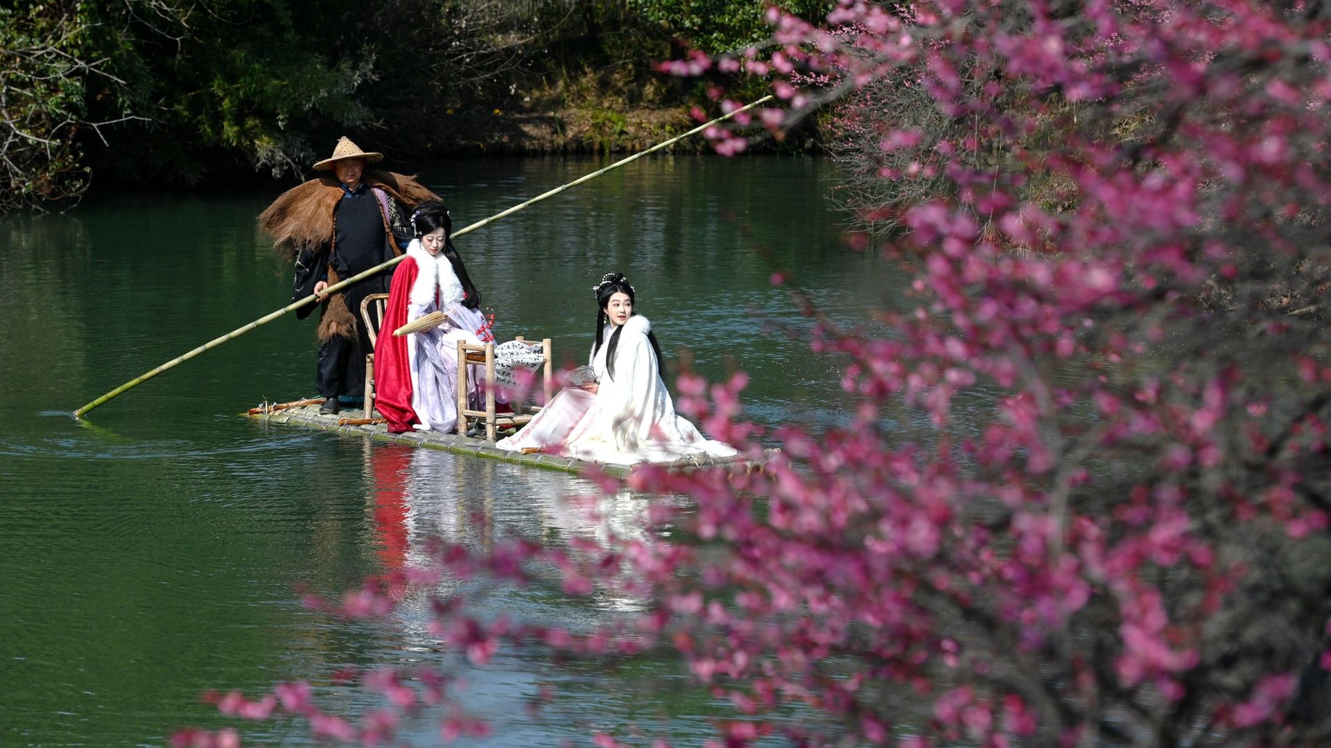 
                                People in traditional costumes glide past plum trees at the Xixi National Wetland Park in Hangzhou, China
                            