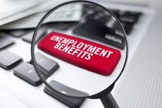 magnifying glass over keyboard with red unemployment benefits key