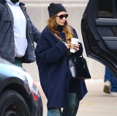 Ashley Olsen in a blue coat, beanine, and socks and sandals