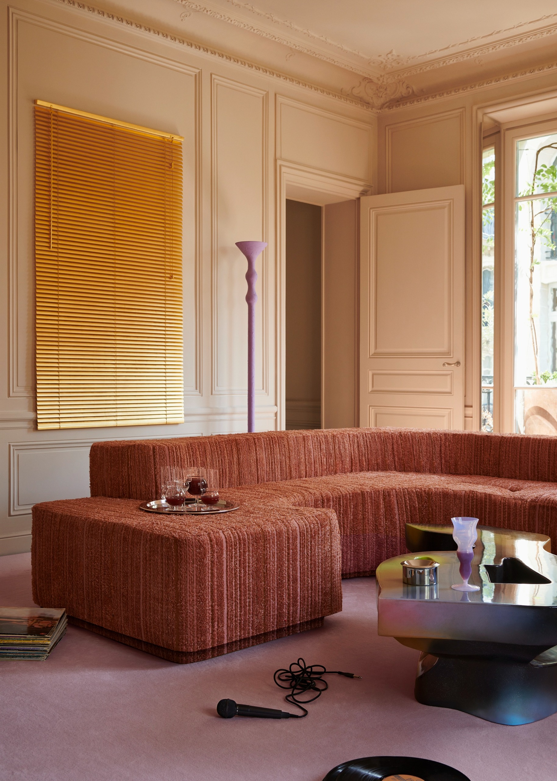 a living room with a texture sofa, a light purple floor, purple floor lamp, yellow blinds, and beige walls