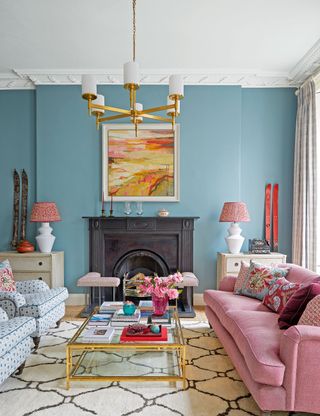 Blue living room with black fireplace, and pink soft furnishings