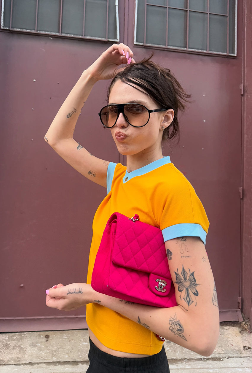 A woman wearing a yellow neon shirt and a neon Chanel bag.
