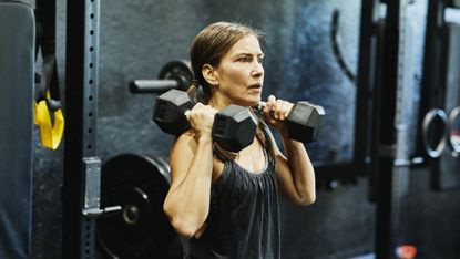 A 40-year old woman doing a dumbbell workout in the gym