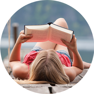 Image of young girl lying on ground reading a book