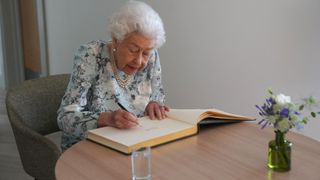 Queen Elizabeth II signs a guestbook during a visit to officially open the new building of Thames Hospice