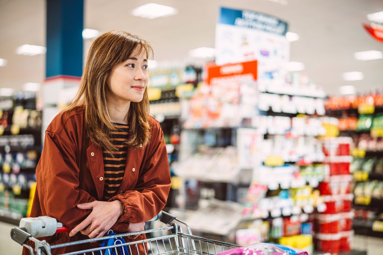 Woman waiting in line for checkout while shopping for groceries in supermarket.