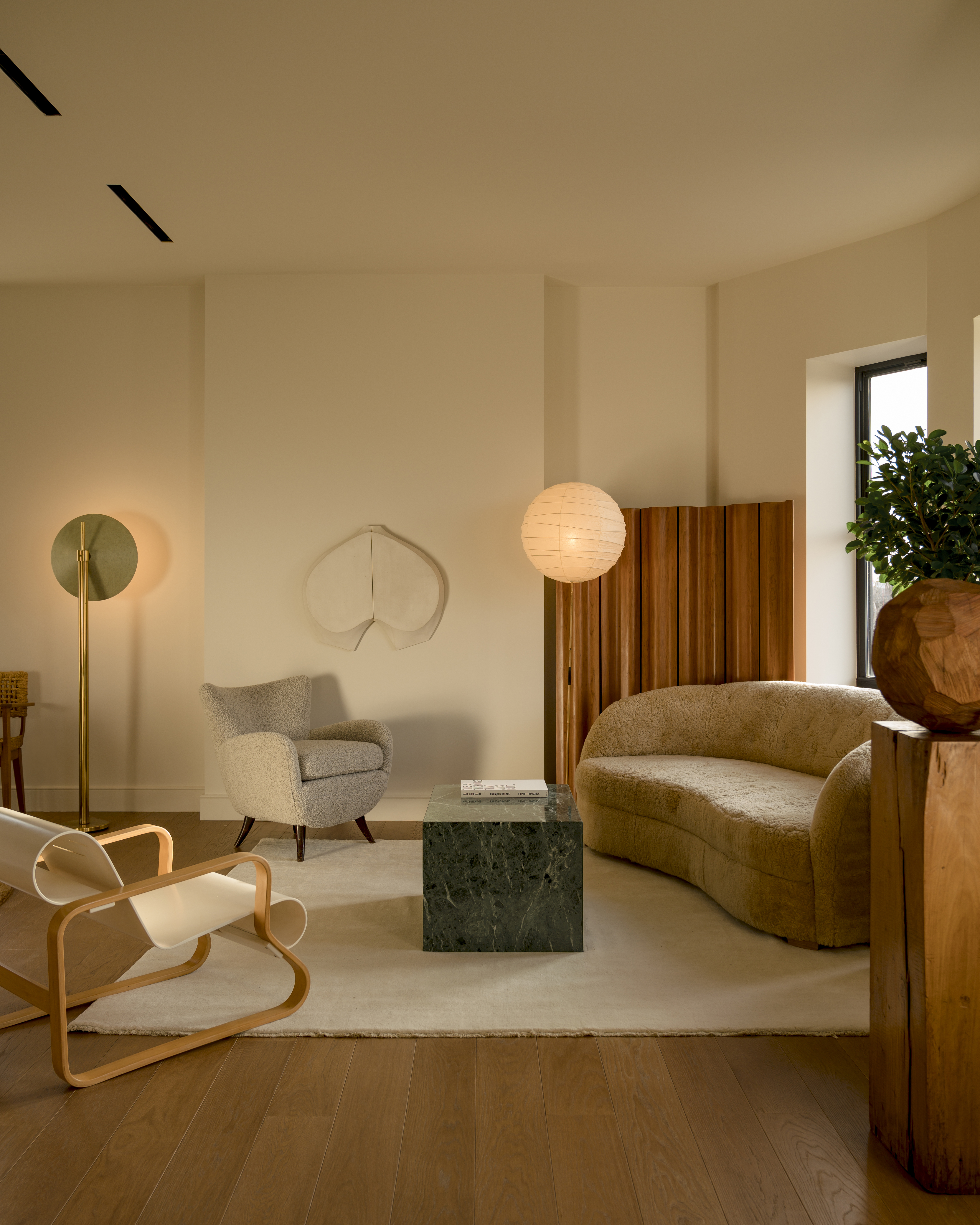 A living room with beige walls, a wooden divider, and warm yellow lights
