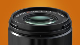 The Fujifilm XF33mm f/1.4 lens on an orange background