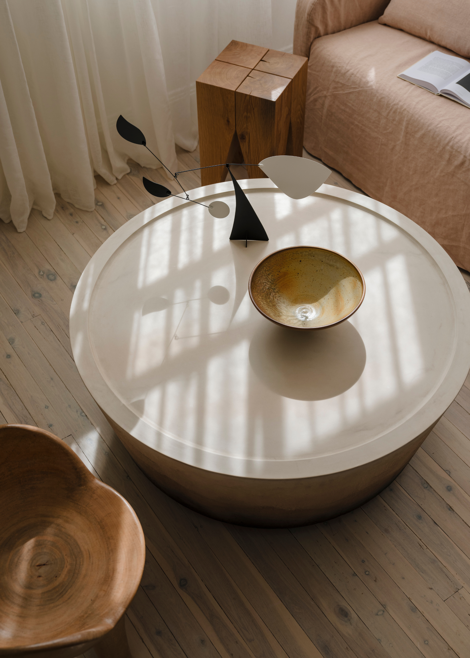 A coffee table with an incense bowl and a decorative stand near a wood table a sofa and a wood stool