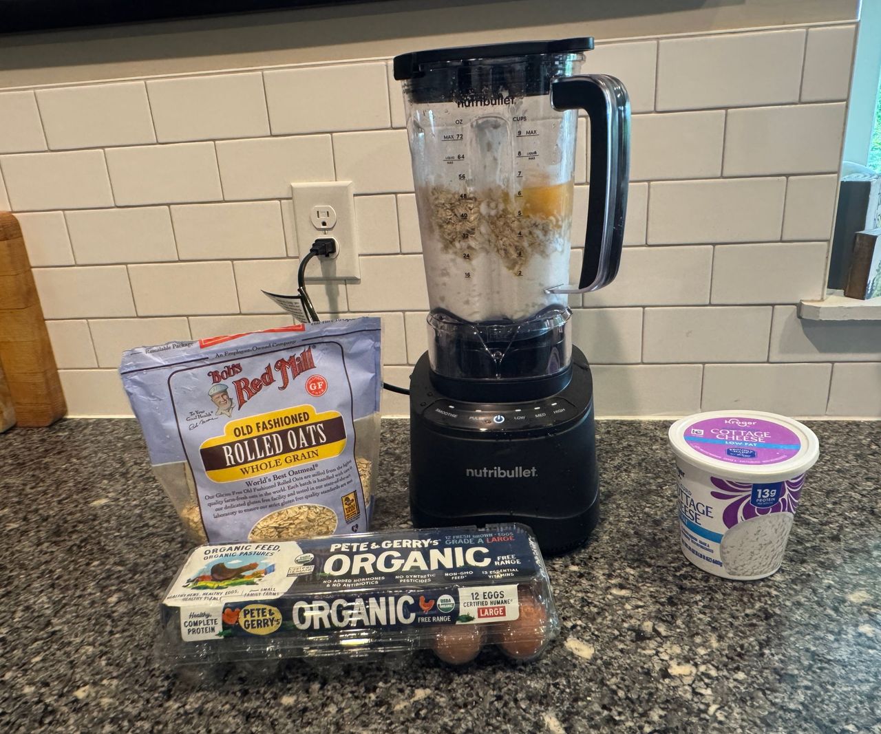 A black blender with eggs, oats, and cottage cheese surrounding it.