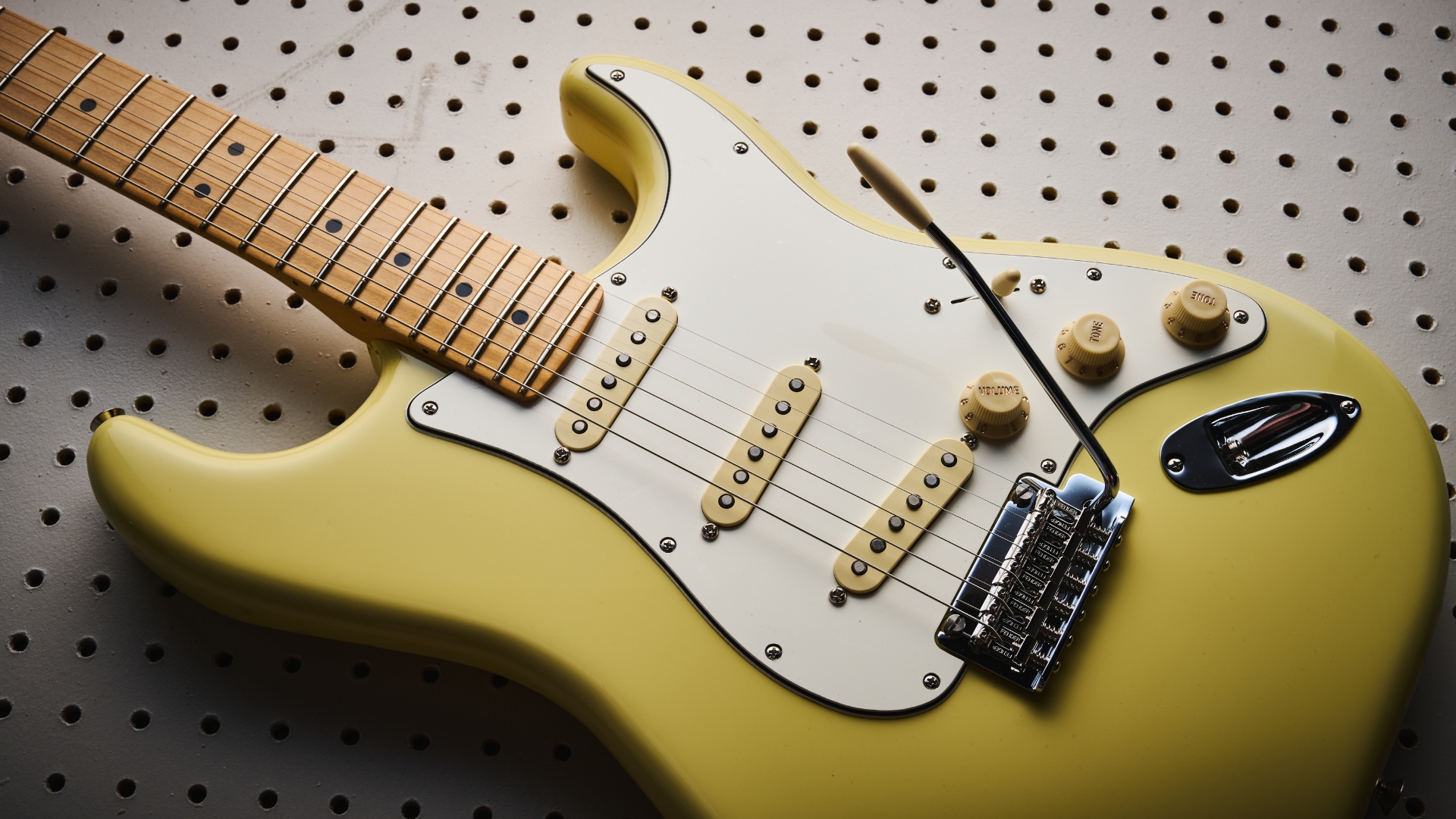 A Fender Player II Stratocaster lying on a white pegboard