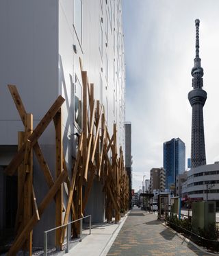 In daylight, wooden batons of One@Tokyo hotel exterior and in background Tokyo Skytree tower