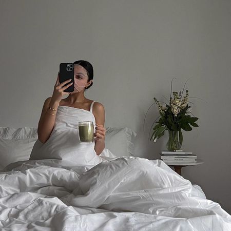 Woman wearing a sheet mask and taking a selfie on an iPhone