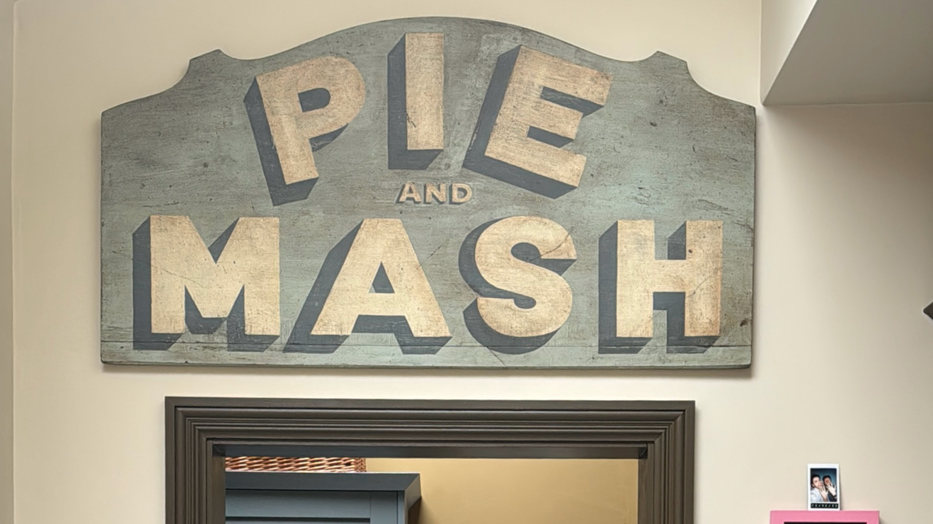 vintage pie and mash sign above a green doorframe