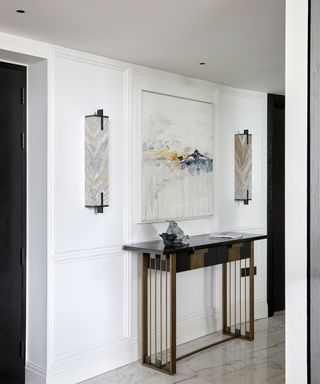 Narrow, white panelled hallway with recessed lights and wall sconces.