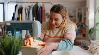 Casually dressed woman sewing at home