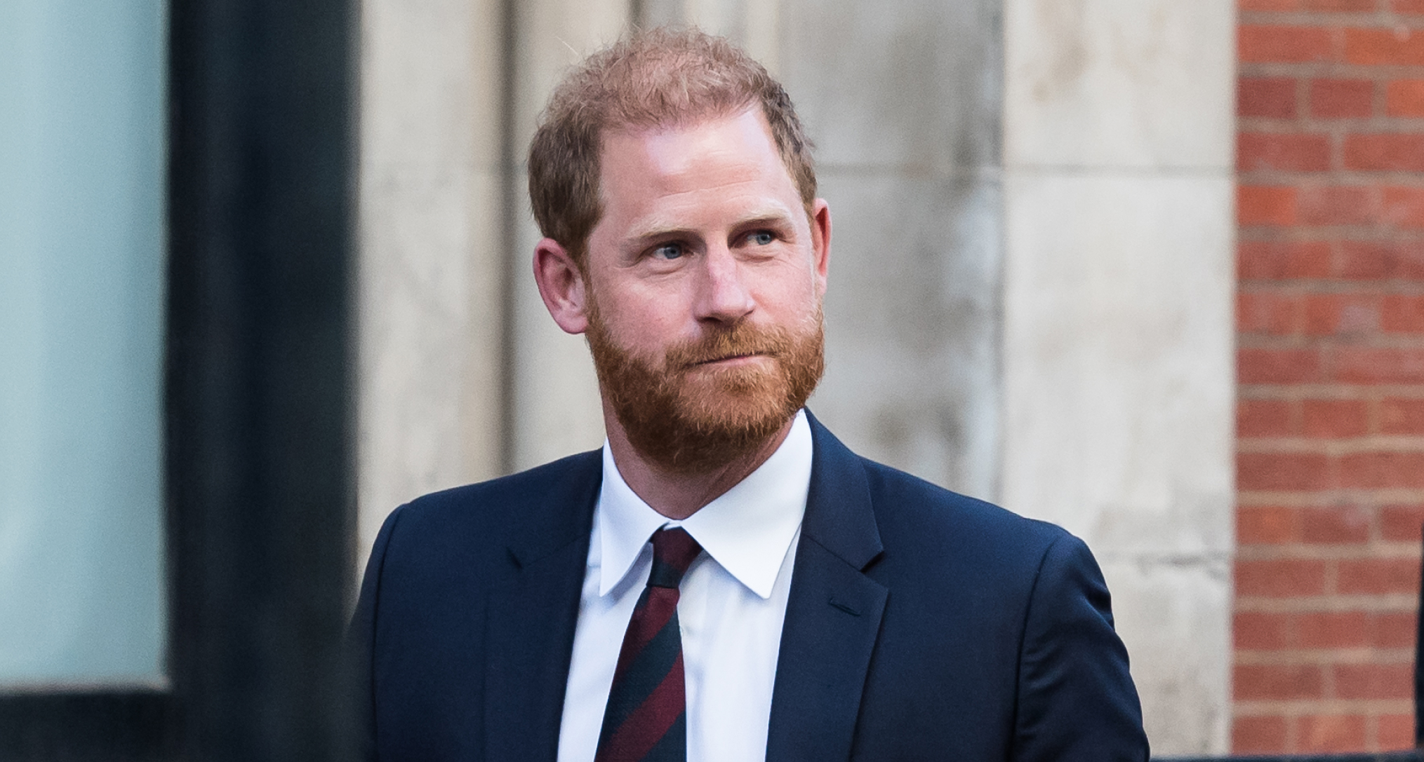 Prince Harry looking up to the right and wearing a blue suit