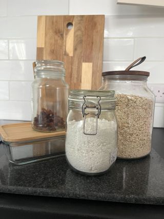 Glass food storage jars filled with sugar, oats, and dried fruit