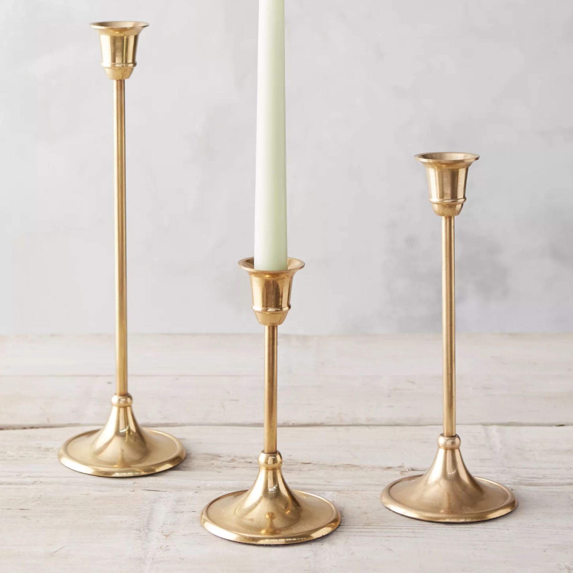 Three antiqued brass candlesticks with trumpet bases