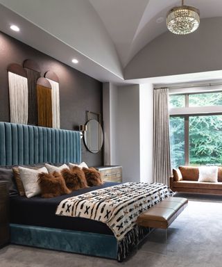 large master bedroom with blue upholstered bed and high ceilings