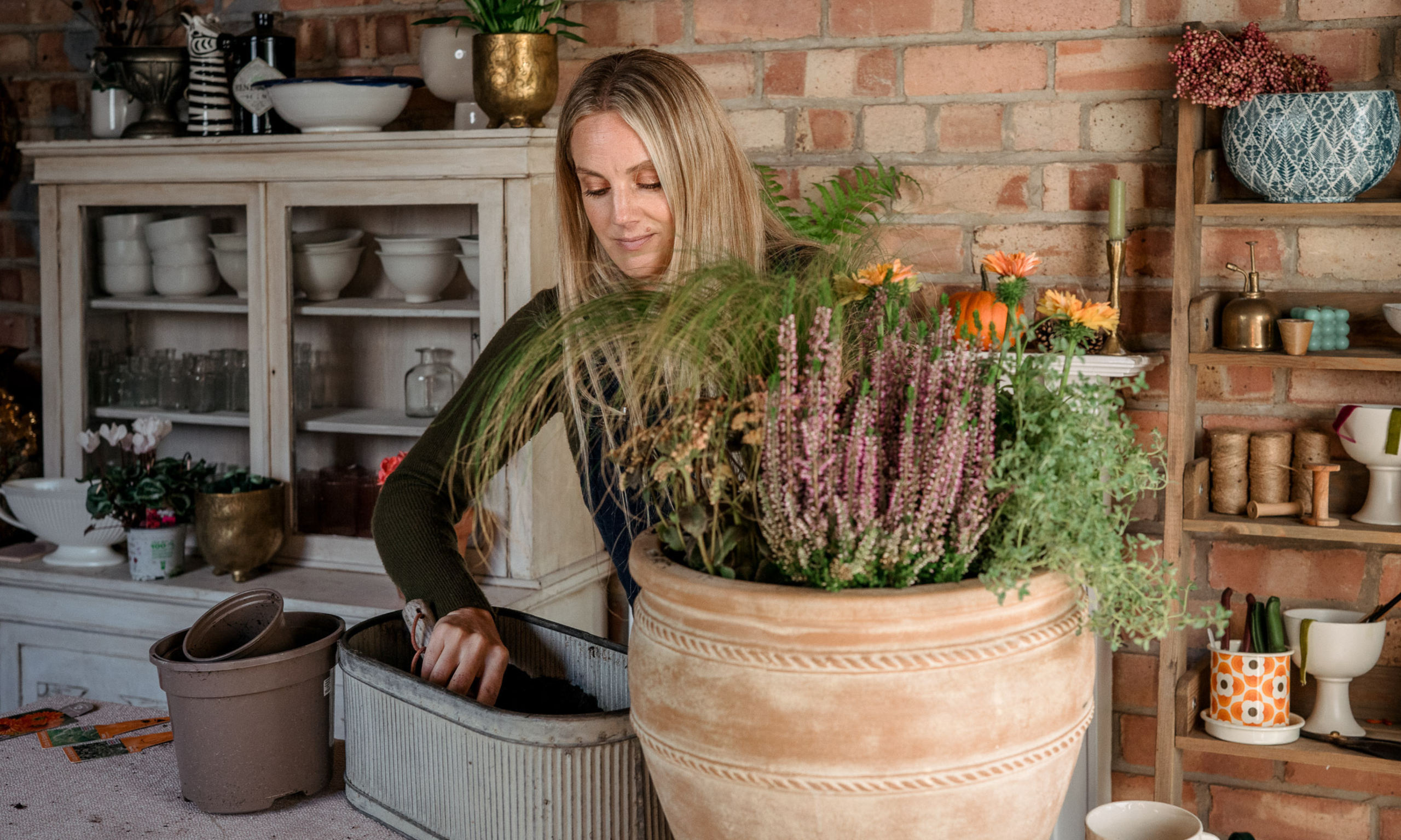 Woman planting up a large terracotta pot with fall plants