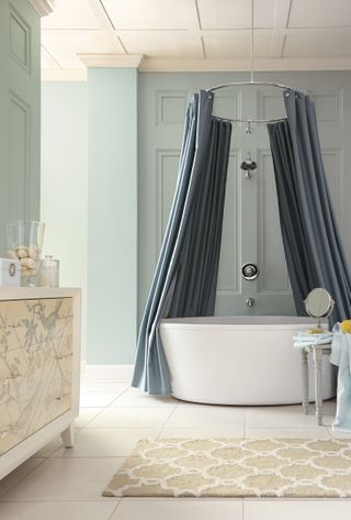 A bathroom with light blue walls and a large oval tub