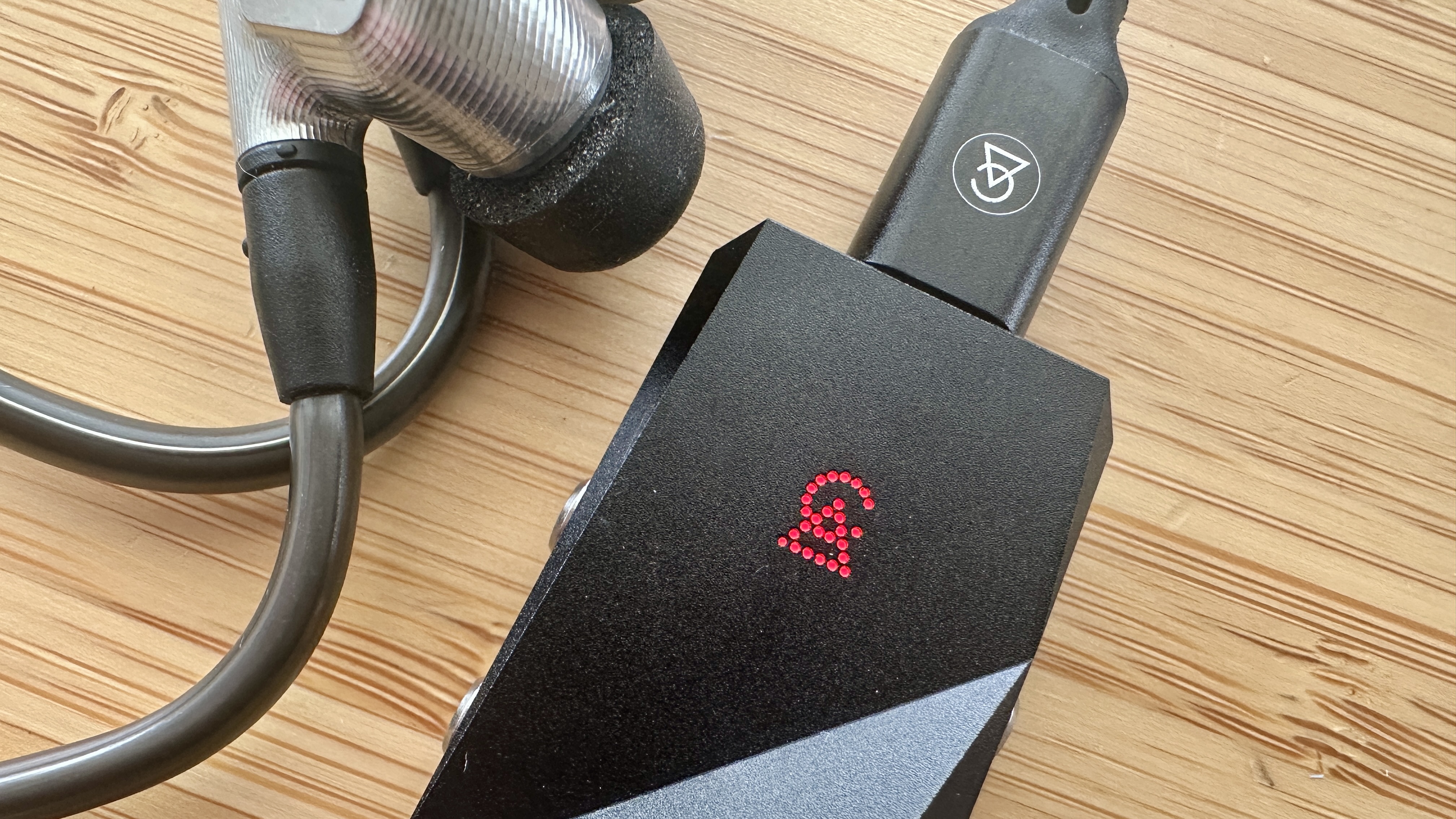 Campfire Audio Relay headphone amp/DAC, connected to Sennheiser IE900 IEMs, on a wooden surface