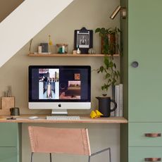 green wall with desk and wooden shelf and computer