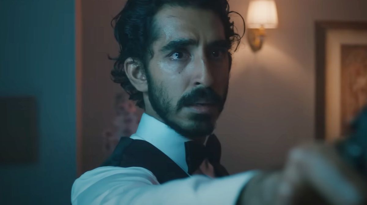 Dev Patel holding a gun with watery eyes in Monkey Man.