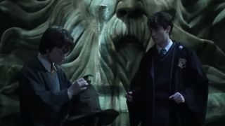Harry holding the sorting hat and Tom Riddle looking at him.