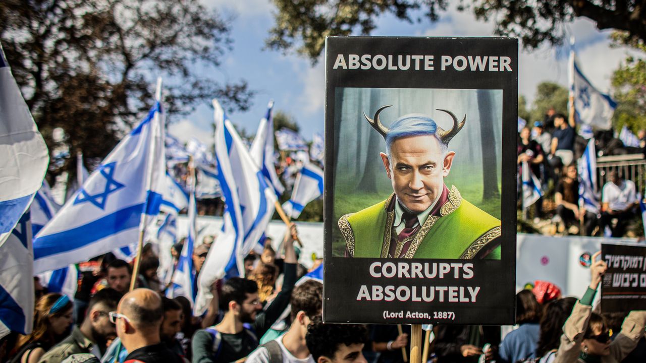 protestor holds sign that reads &amp;quot;absolute power corrupts absolutely&amp;quot;